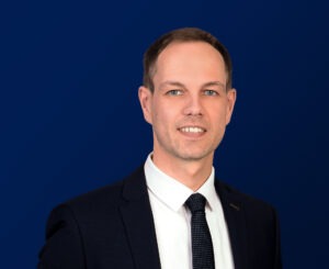 Matthias Kneissl, Fachanwalt für Steuerrecht und Steuerberater, in dunklem Anzug mit weißem Hemd und dunkler Krawatte vor dunkelblauem Hintergrund.