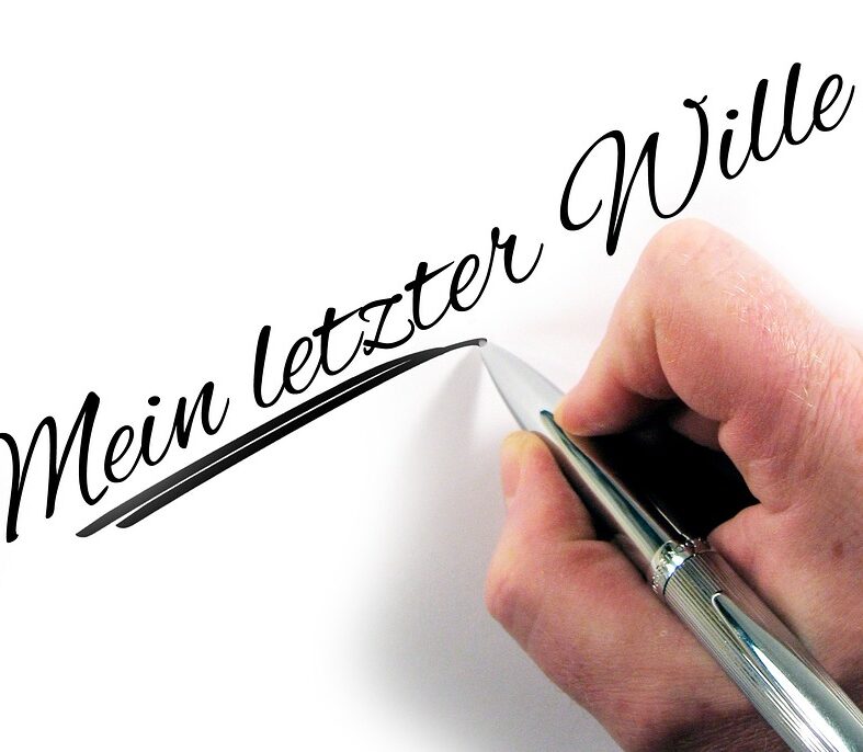 Es ist eine Hand abgebildet, die einen Kugelschreiber hält und damit die Worte "Mein letzter Wille..." schreibt.